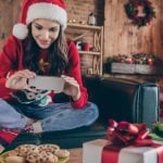 Woman Plays On Cell Phone While Sitting on Couch In Santa Hat