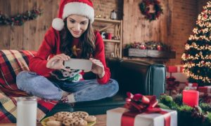 Woman Plays On Cell Phone While Sitting on Couch In Santa Hat