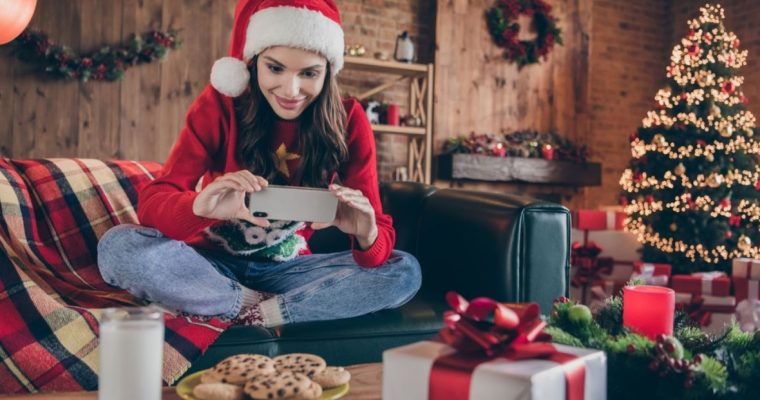 Woman Plays On Cell Phone While Sitting on Couch In Santa Hat