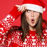 Woman With Surprised Look Wears Santa Hat And Christmas Sweater