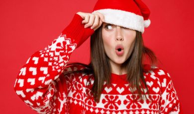 Woman With Surprised Look Wears Santa Hat And Christmas Sweater