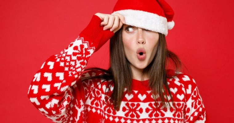 Woman With Surprised Look Wears Santa Hat And Christmas Sweater