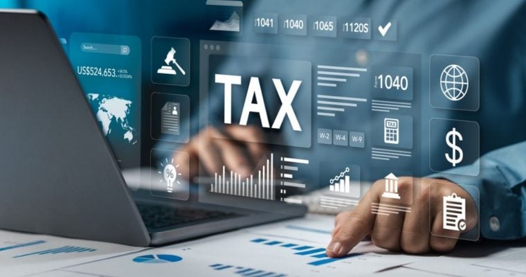 Man Points to Graph On Paper Sits In Front of Laptop with "Tax" Digital Graphics Overlay