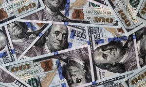 Several $100 Bills Lay Face Up Layered On Top of Each Other