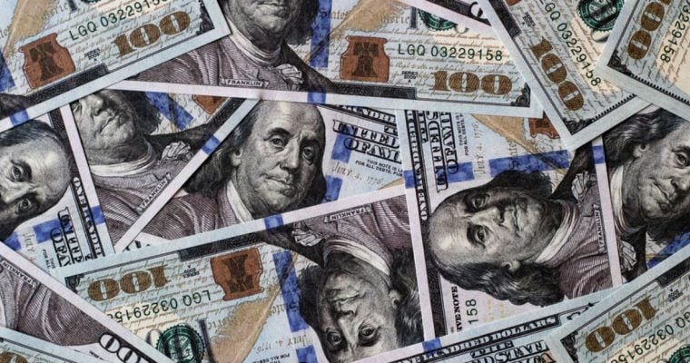 Several $100 Bills Lay Face Up Layered On Top of Each Other