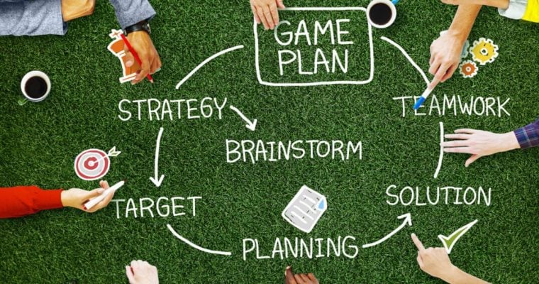 Circle of Hands Around a Game Plan On Green Grass