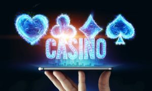 Suit of Playing Card Symbols and "Casino" Above Cell Phone Held By Fingers