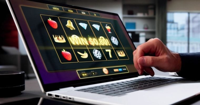 Online Slot Game Displayed on Laptop with Man's Hand Over Keyboard
