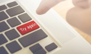 Man's Finger Set to Press Red Try Again Button on Laptop