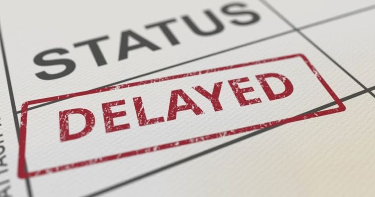 Close Up of White Document Reading Status Delayed in Black and Red Letters