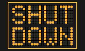Road Sign Reads Shut Down in Yellow L.E.D. Lights on Black Background