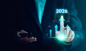 Business Man Points to Arrow with 2026 Above it While Holding Cell Phone