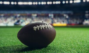 Isolated American Football Sits On Grass Field Inside Stadium