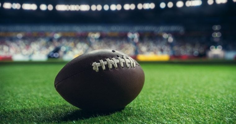 Isolated American Football Sits On Grass Field Inside Stadium
