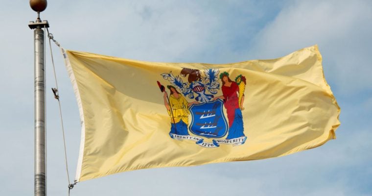 Yellow State Flag of New Jersey Waves in the Wind Against Cloudy Blue Sky