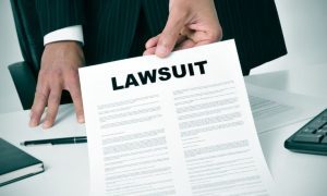 Man in Suit Holds Paper Reading Lawsuit Inside Office