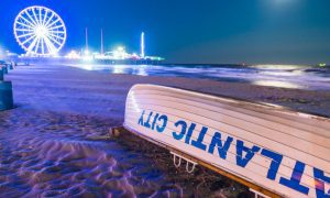 Ferris Wheel and City Lights Glow In the Background On Sandy Beach in Atlantic City, New Jersey