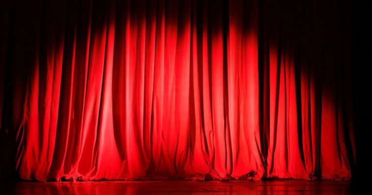 Spotlight Shines Toward Bottom of Draped Red Stage Curtain