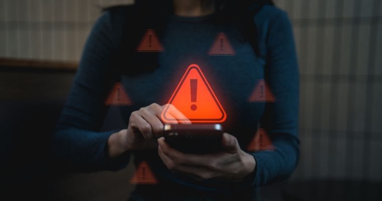 Woman Holding Cell Phone with Red Warning Icons Hovering Around It