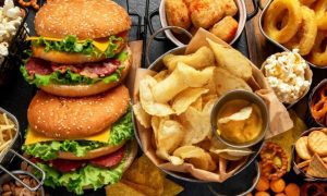 Close Up of Burgers, Chips, Onion Rings, and Various Other Foods on Table