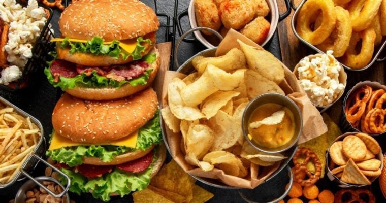Close Up of Burgers, Chips, Onion Rings, and Various Other Foods on Table