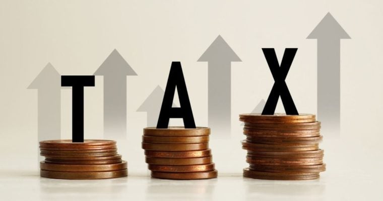 Upward Pointing Arrows Behind Stacks of Copper Coins and the Word Tax