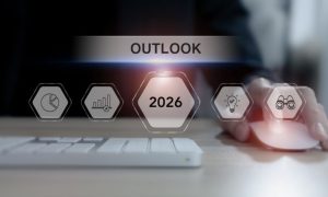 Outlook 2026 Text Overlay on Image of Man Sitting In Front of Laptop Keyboard