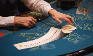 Casino Dealer Fans Deck of Playing Cards on Blue Poker Table