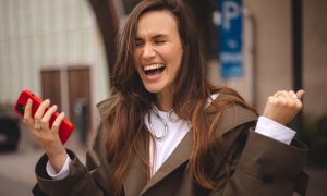Woman With Excited and Happy Expression Holds Red Cell Phone
