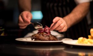 Man's Hands Plates a Perfectly Cooked Steak Inside Kitchen