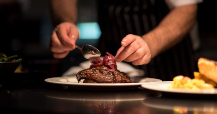 Man's Hands Plates a Perfectly Cooked Steak Inside Kitchen