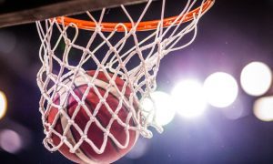 Bright Stadium Lights Shine On Close Up of Basketball Netting a Hoop