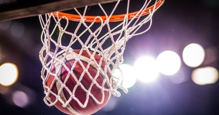 Bright Stadium Lights Shine On Close Up of Basketball Netting a Hoop