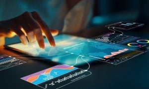 Woman Touches Tablets on Table Displaying Various Data Sets and Graphs