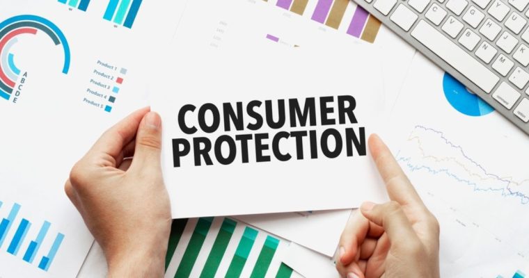 Desk With White Keyboard and Papers with Graphs Show Hands Holding Card Reading Consumer Protection