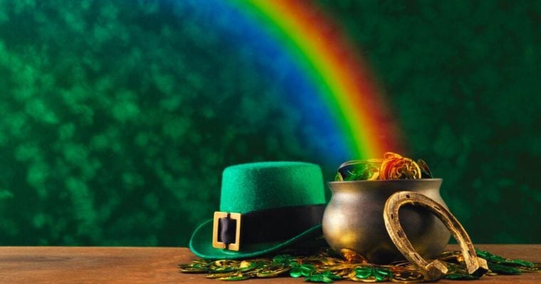 Rainbow Falls on Pot of Gold Coins Sitting Beside Leprechaun's Hat and Horseshoe