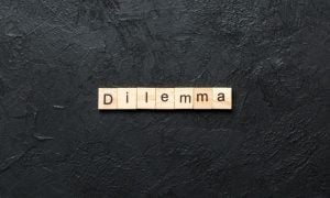 Light Wood Colored Blocks Spell Dilemma Centered on Black Background