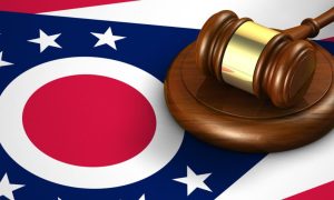 Wooden Judge's Gavel with Gold Metal Detail Sits On top of Ohio State Flag