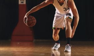 Young Man Bounces a Basketball On Empty Court
