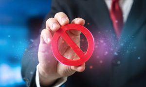 Man Wearing a Suit with Red Tie Holds a Red Banned Logo