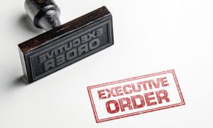 Rubber Stamp with Red Ink Says Executive Order on White Background