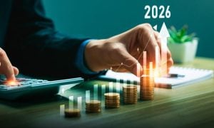 Man Sitting at Desk Uses Calculator to Count Stacked Coins with Digital Overlay of Bar Graph and 2026