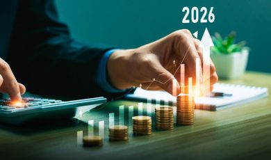 Man Sitting at Desk Uses Calculator to Count Stacked Coins with Digital Overlay of Bar Graph and 2026