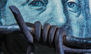 Metal Barb Wire Lays Across US Banknote Background
