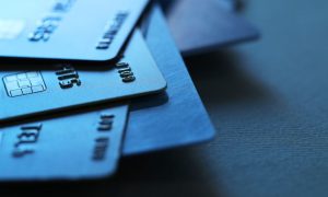 Light Reflects Off Of 3 Credit Cards in a Pile on Black Desk