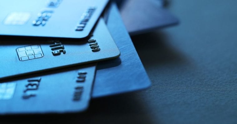 Light Reflects Off Of 3 Credit Cards in a Pile on Black Desk