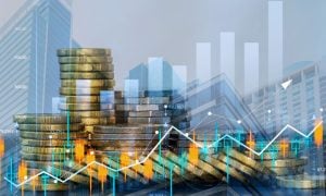 Double Exposed Image With Stacks of Gold Coins, Cityscape and Various Financial Graphs Overlaid