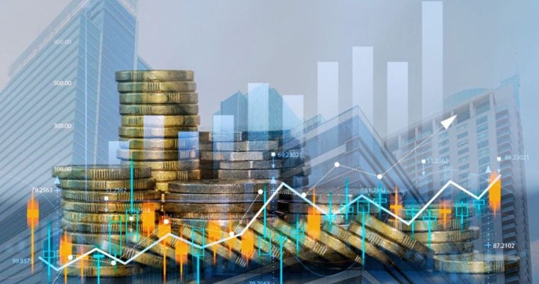 Double Exposed Image With Stacks of Gold Coins, Cityscape and Various Financial Graphs Overlaid