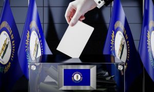 Man's Hand Place White Envelope Into Clear Box With Kentucky State Flags in Background