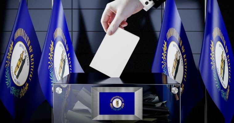 Man's Hand Place White Envelope Into Clear Box With Kentucky State Flags in Background